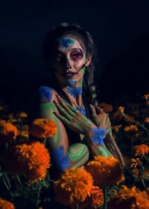 Artistic portrait of a woman with Catrina makeup and flowers at night, celebrating Mexican culture.